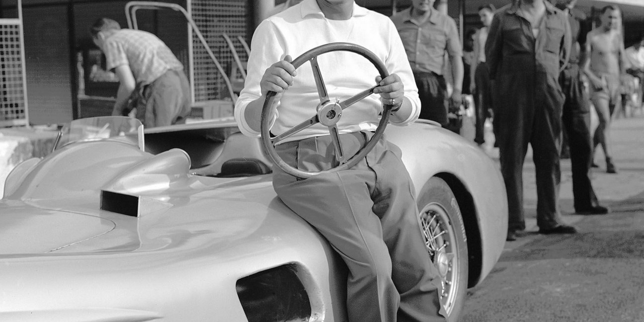 Mercedes-Benz Rennfahrer Hans Herrmann im August 1955 bei Versuchsfahrten auf dem Autodrom in Monza, neben dem Formel-1-Rennwagen W 196 R mit Stromlinienkarosserie.