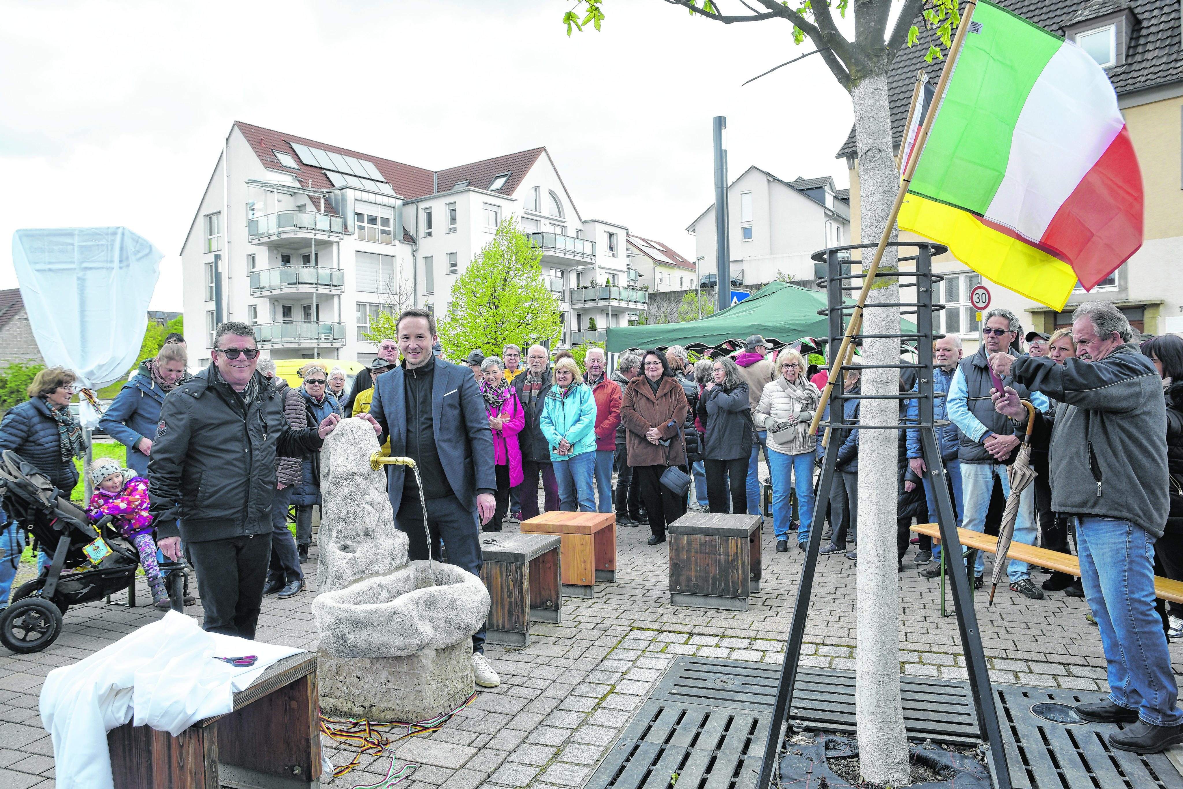 Einweihung des Freundschaftsbrunnens auf dem Magstadter Gusti-Platz. Celenzas Bürgermeister Walter Di Laudo (mit Sonnenbrille) und Magstadts Bürgermeister Florian Glock (rechts neben dem Brunnen) enthüllten erst den noch trockenen Brunnen und drehten dann in einem Schacht in der Maichinger Straße den Wasserhahn auf.