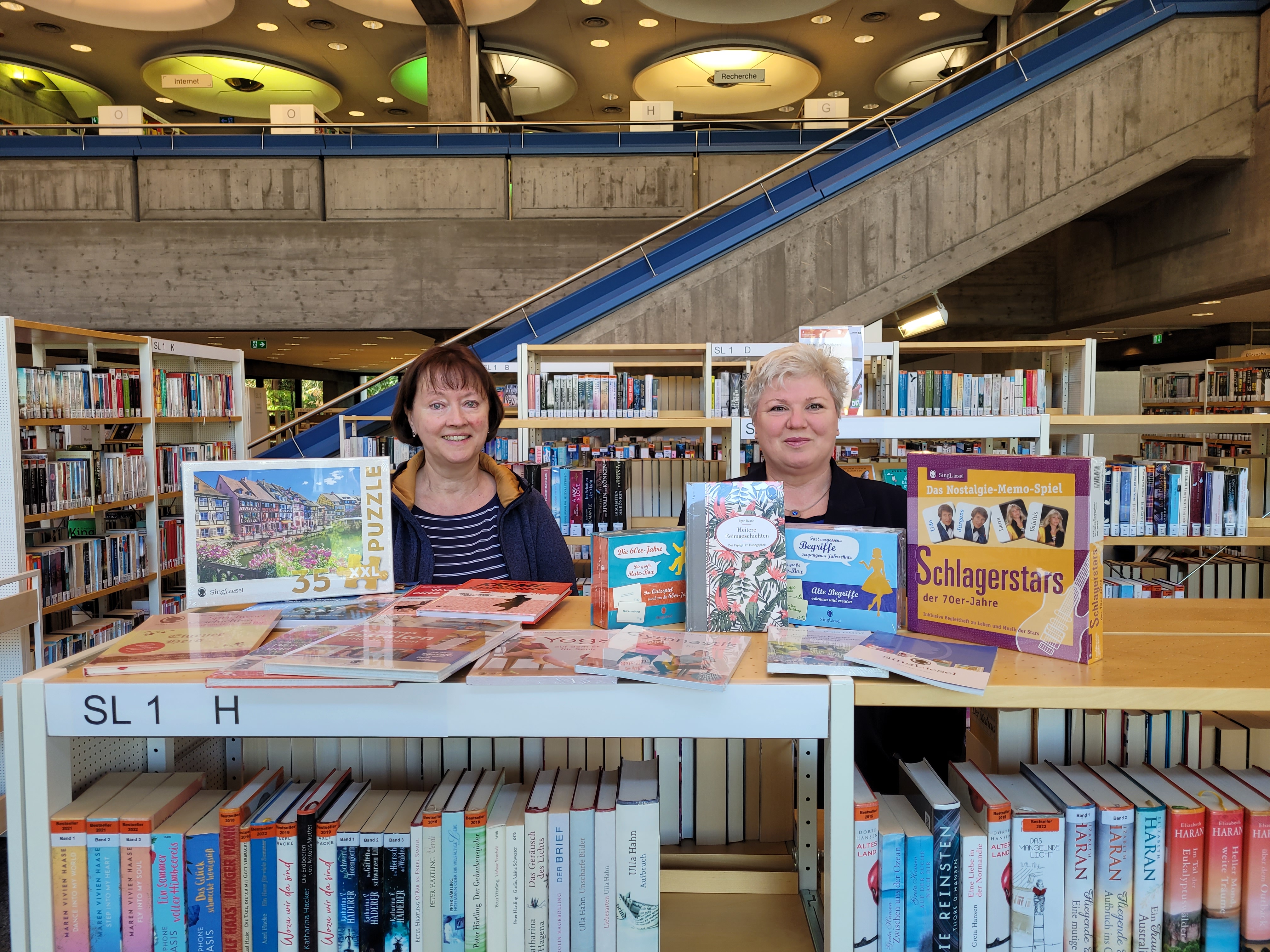 Sabine Dölker, Mitarbeiterin der Tagespflege der Sozialstation, und Brigitte Kraft, Leiterin der Stadtbibliothek Sindelfingen, freuen sich über das Spendenpaket des Sing-Liesel -Verlags. Bild: Stadtbibliothek Sindelfingen