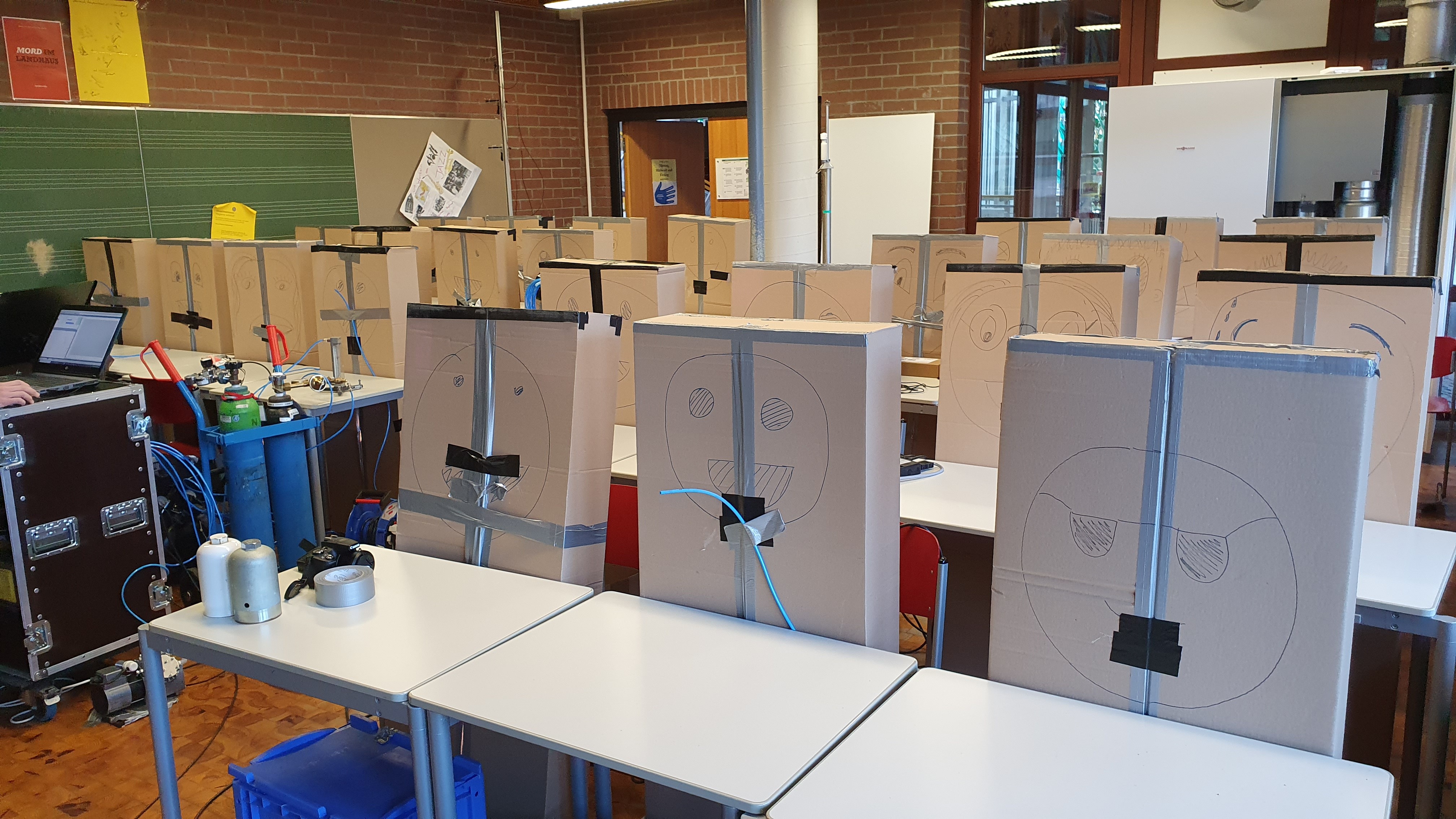 Eine Schulklasse, die aus Pappkartons besteht, im Dienst der Wissenschaft. Rechts hinten ist ein kombiniertes Luftreinigungs- und Lüftungsgerät zu sehen. Bilder: z