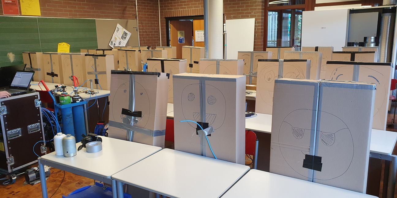 Eine Schulklasse, die aus Pappkartons besteht, im Dienst der Wissenschaft. Rechts hinten ist ein kombiniertes Luftreinigungs- und Lüftungsgerät zu sehen. Bilder: z