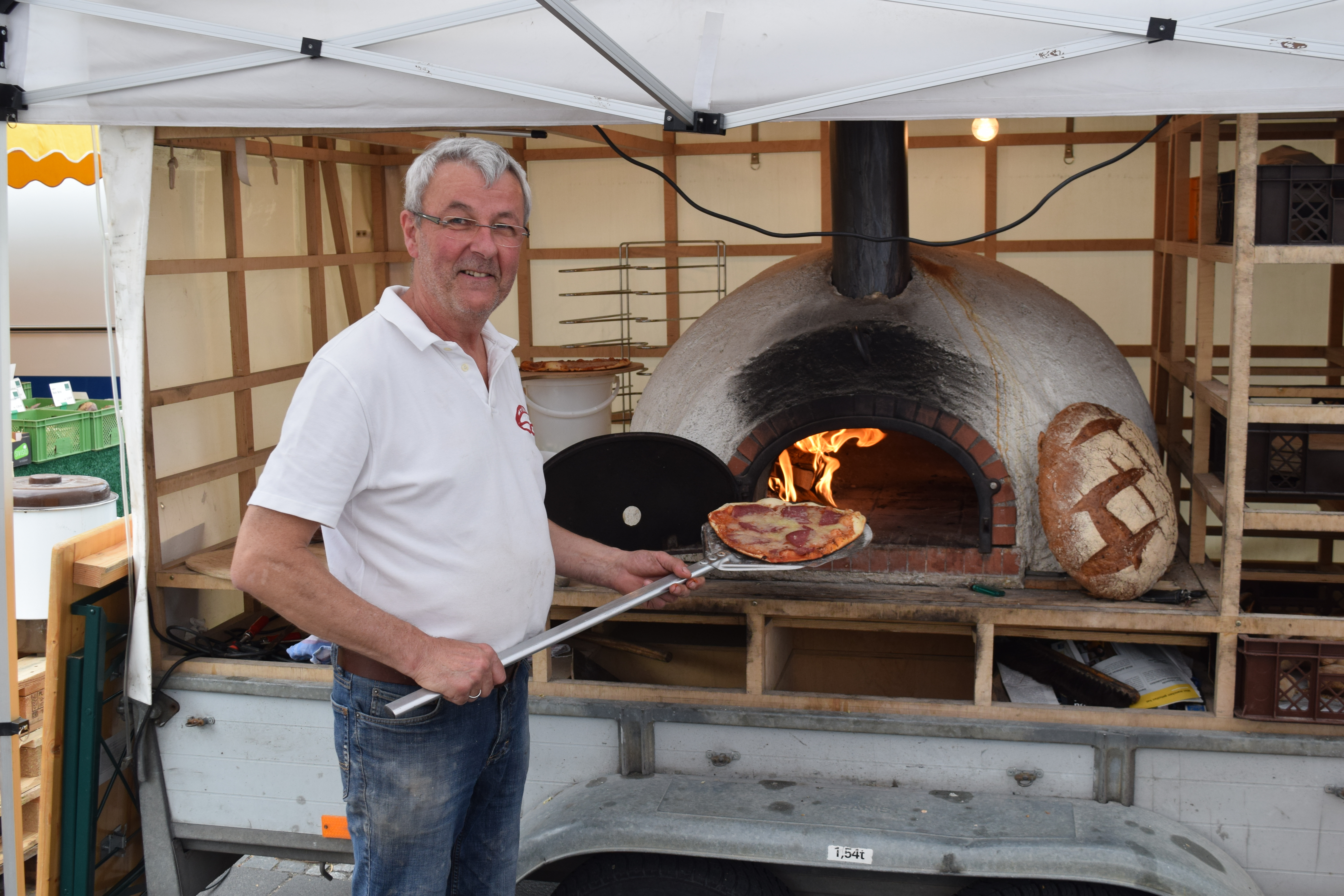 Bäckermeister Theo Noller schiebt eine Pizza Salami in den Holzbackofen.
