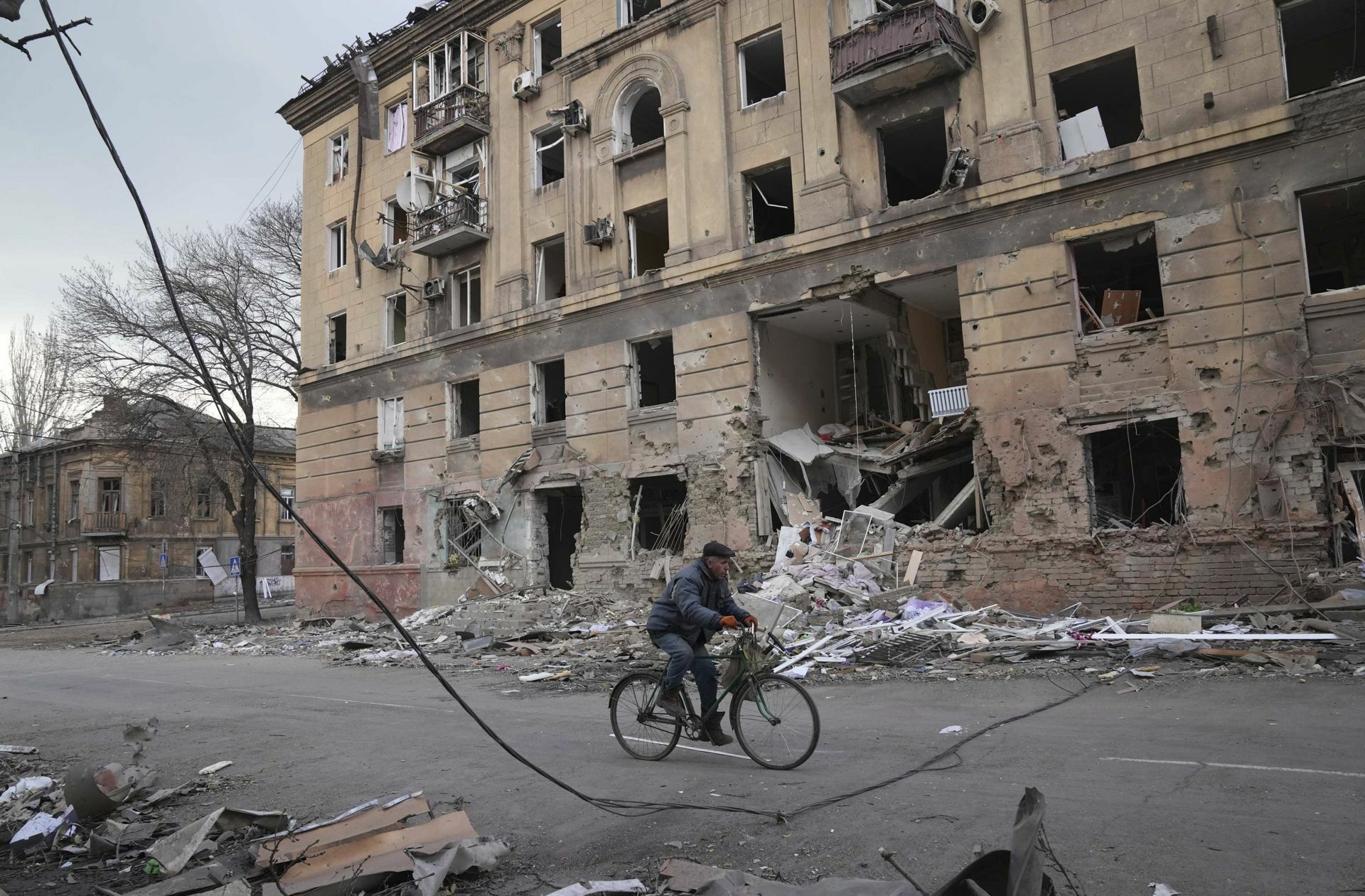 Ein Mann fährt  mit dem  Rad durch das zerstörte Mariupol.
