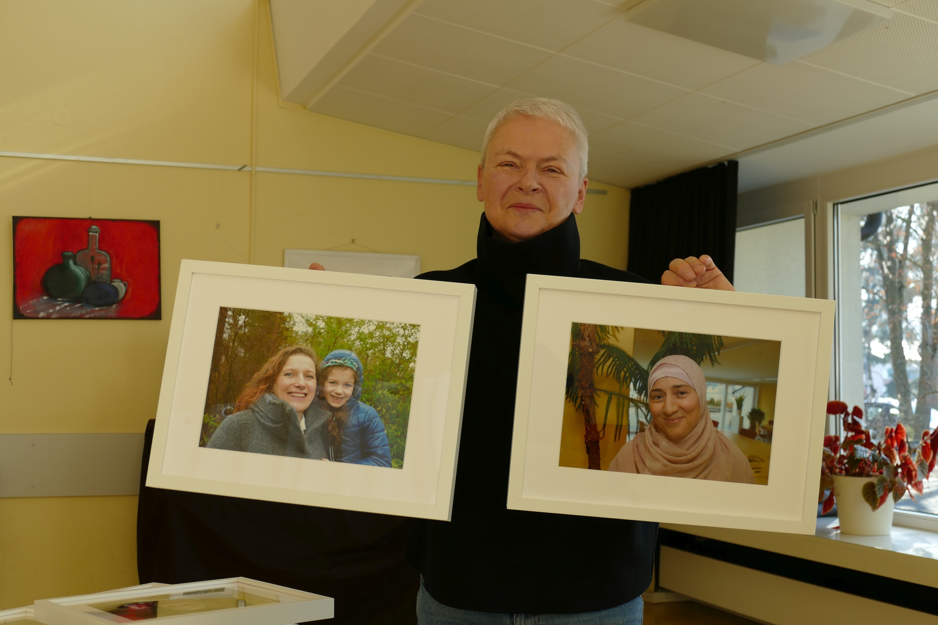 Sibylle Siegner mit zwei Bildern von Mitabeiterinnen, die zur Ausstellung "Heimat" schreiben. Bild: Lück