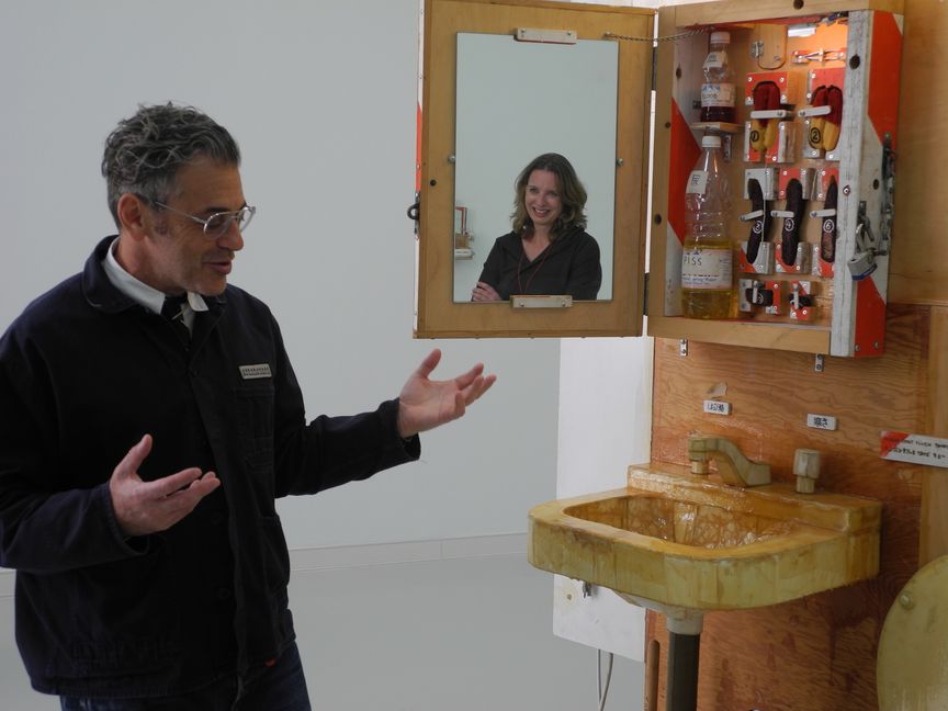 Tom Sachs erklärt „Lil‘ T’s Toilet Town“, im Spiegel Kuratorin Svenja Frank.