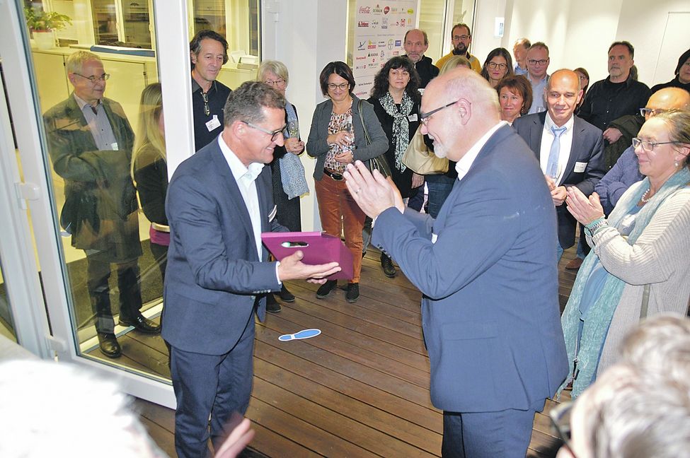 Weil der Stadts Beigeordneter Jürgen Katz (im Vordergrund, rechts) bedankt sich mit einem kleinen Geschenk und viel Beifall bei Wolftechnik-Geschäftsführer Peter Krause (vorne links) dafür, dass er bei der Türöffner-Veranstaltung in die Rolle des Gastgebers geschlüpft ist. Bild: Reichert