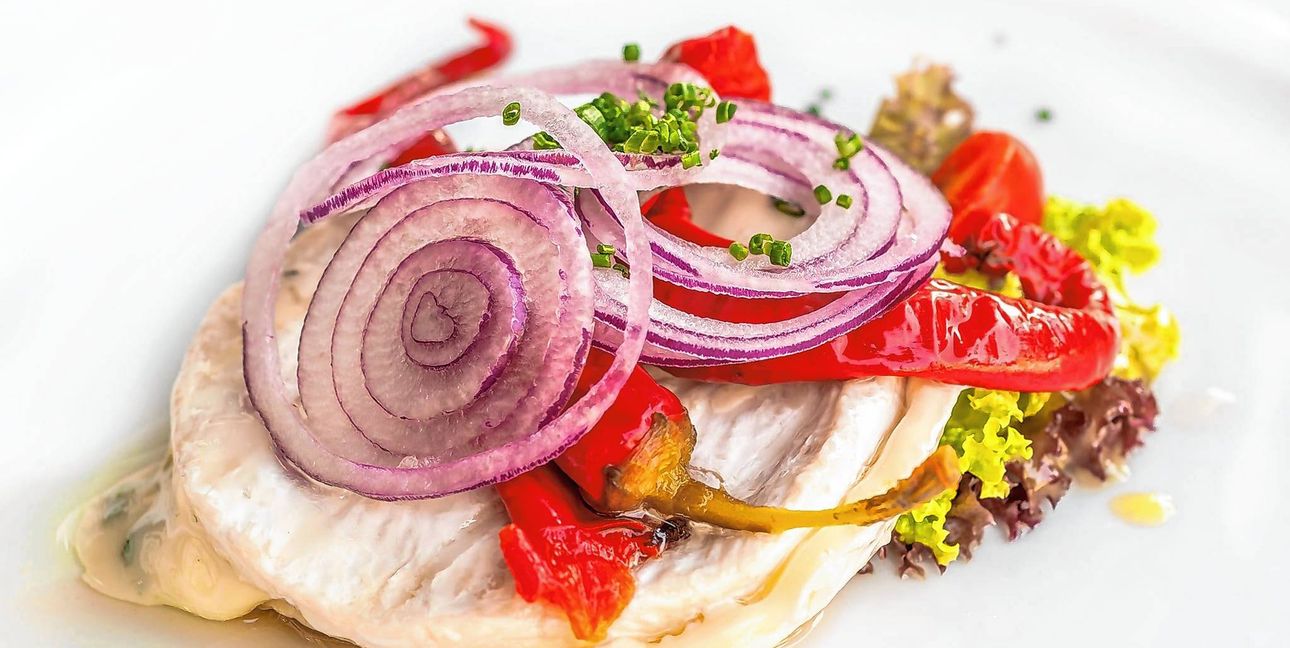 Zwiebelringe, Paprika und ein Salatblatt gehören auf den Käse. Bild:  Adobe Stock