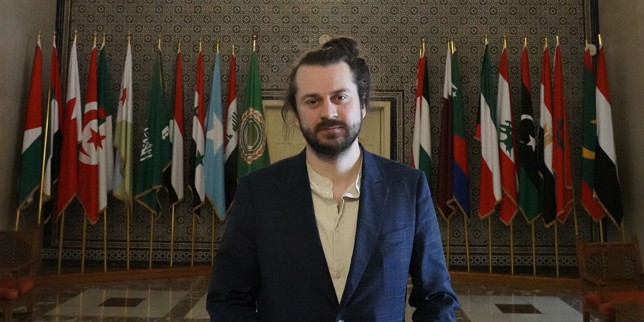 Tobias Bacherle in der Eingangshalle der Arabischen Liga mit Flaggen der Mitgliedsstaaten.