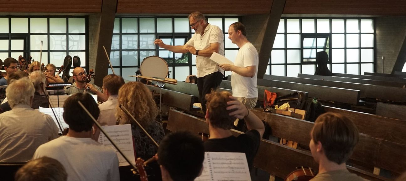 Matthias  Hanke dirigiert bei einer Orchesterprobe für das Biennale-Oratorium. Neben ihm steht Komponist Christoph Reuter. Bild: Heiden