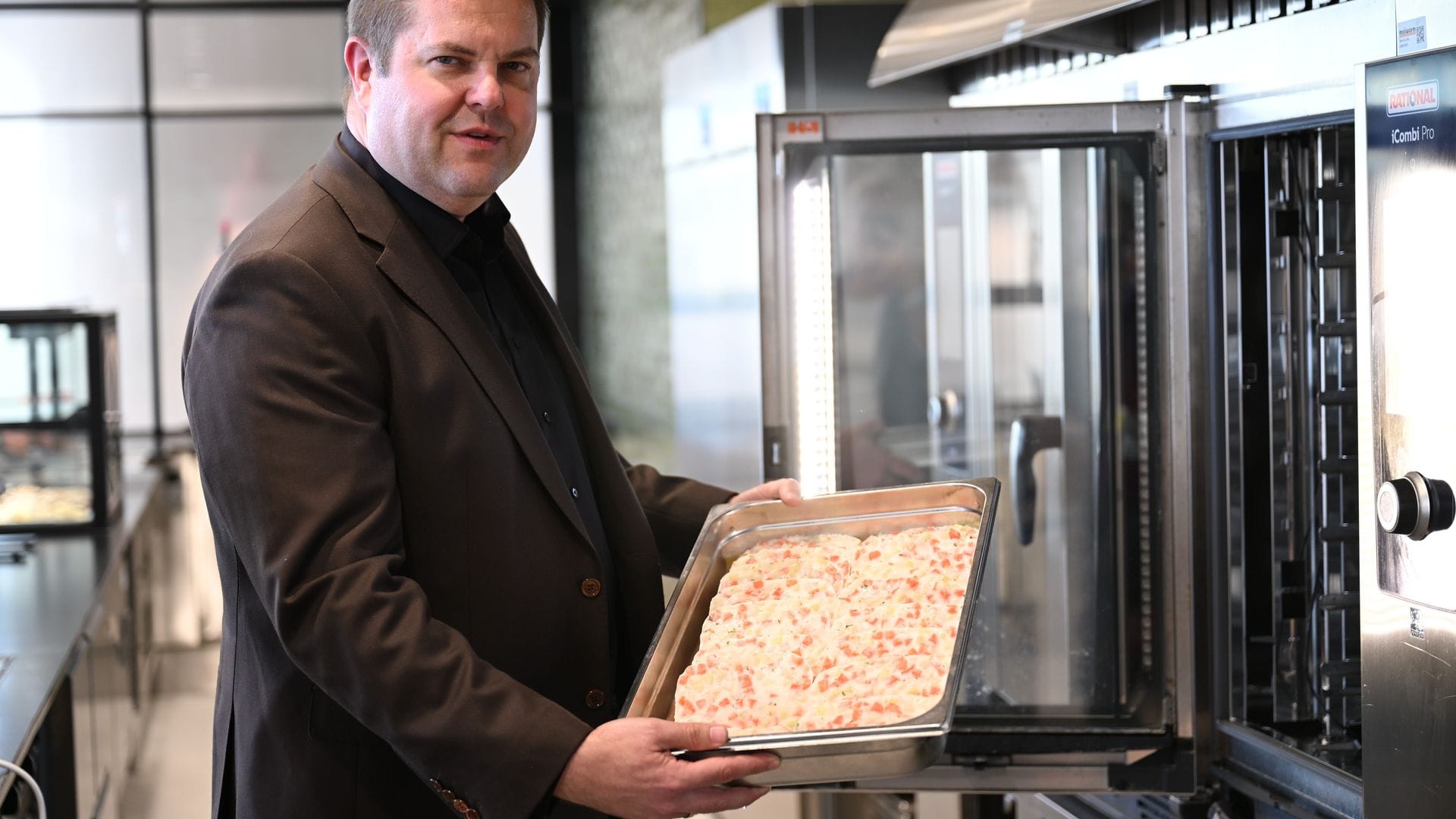 Firmenchef Jan-Peer Laabs hält im Betriebsrestaurant der Apetito-Zentrale eine Schale mit Lachs-Auflauf in der Hand.