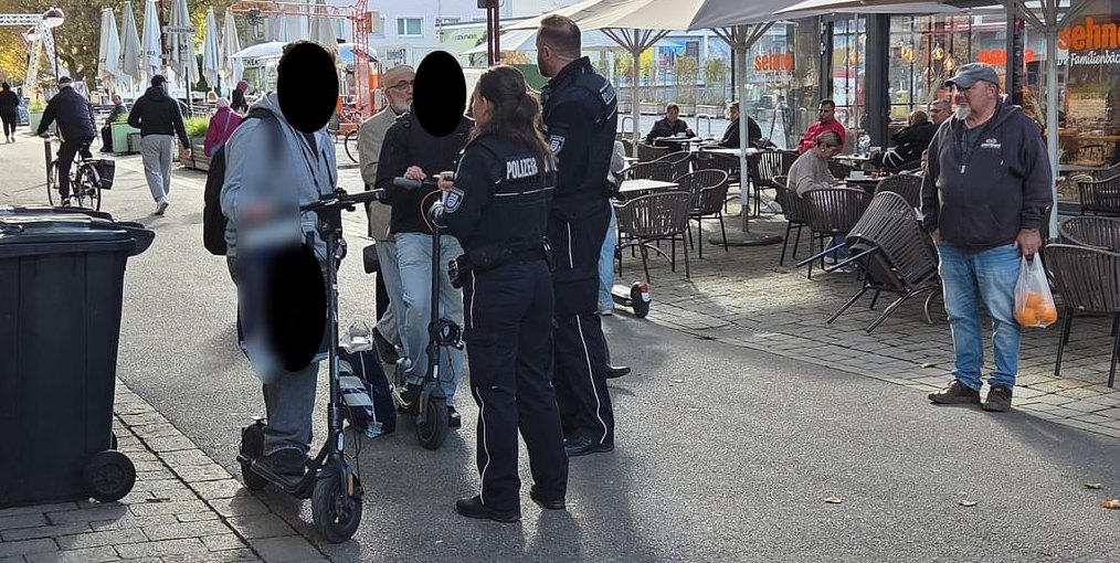 Die Kollegen Scheele und Kretz vom Vollzugsdienst im Gespräch mit E-Scooter-Fahrern. Rechts die Bäckerei in der Unteren Vorstadt 5.