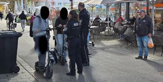 Die Kollegen Scheele und Kretz vom Vollzugsdienst im Gespräch mit E-Scooter-Fahrern. Rechts die Bäckerei in der Unteren Vorstadt 5.
