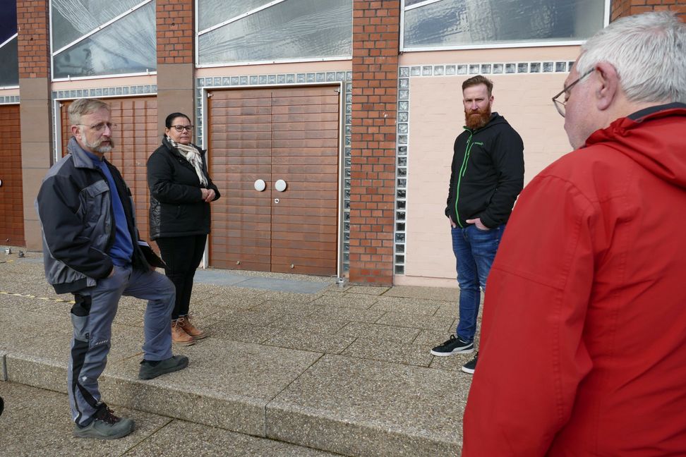 Glasmalermeister Wolf Bay, Architektin Andrea Mink, Gebäudemanager Stefan Seitter und Gemeindemitglied Manfred Schuck (von links). Im untersten Fensterteil über der zweiten Tür sind Schäden zu sehen.  Bilder: Lück
