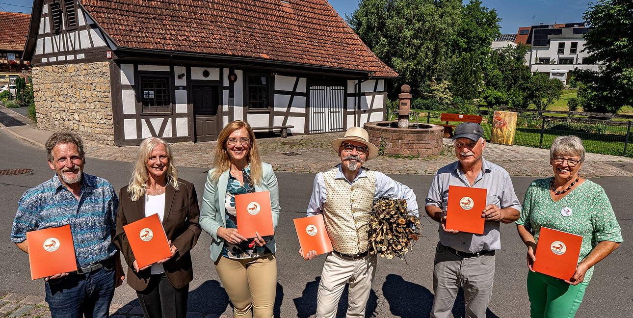 Vorstellung des Dachteler Jubiläumsbuches vom Arbeitskreis vor dem Backhaus und dem Dorfbrunnen von Dachtel. Von links: Ortsvorsteher Ulrich Eisenhardt, Maggie Jarak, Bürgermeisterin Helena Österle, Otto Kühnle, der gleich ein Büschele Holz zum Anzünden im Backhaus mitbrachte, der frühere Ortsvorsteher Ralf Böhret und Birgit Breitling.