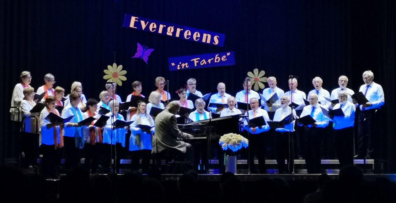 Die Sängerinnen und Sänger des Dahersheimer Liederkranzes auf der mit Schwarzlicht beleuchteten Bühne in der Festhalle. Bild: z