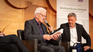 Ministerpräsident Winfried Kretschmann liest aus seinem Hannah-Arendt-Buch, und Ex-Vizekanzler Robert Habeck hält ihm das Mikrofon.
