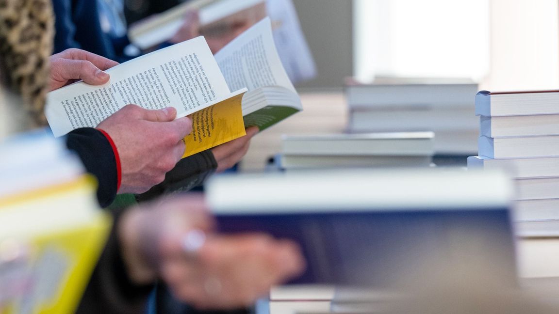 Besucher der Leipziger Buchmesse lesen im März 2024 am Stand eines Verlages.
