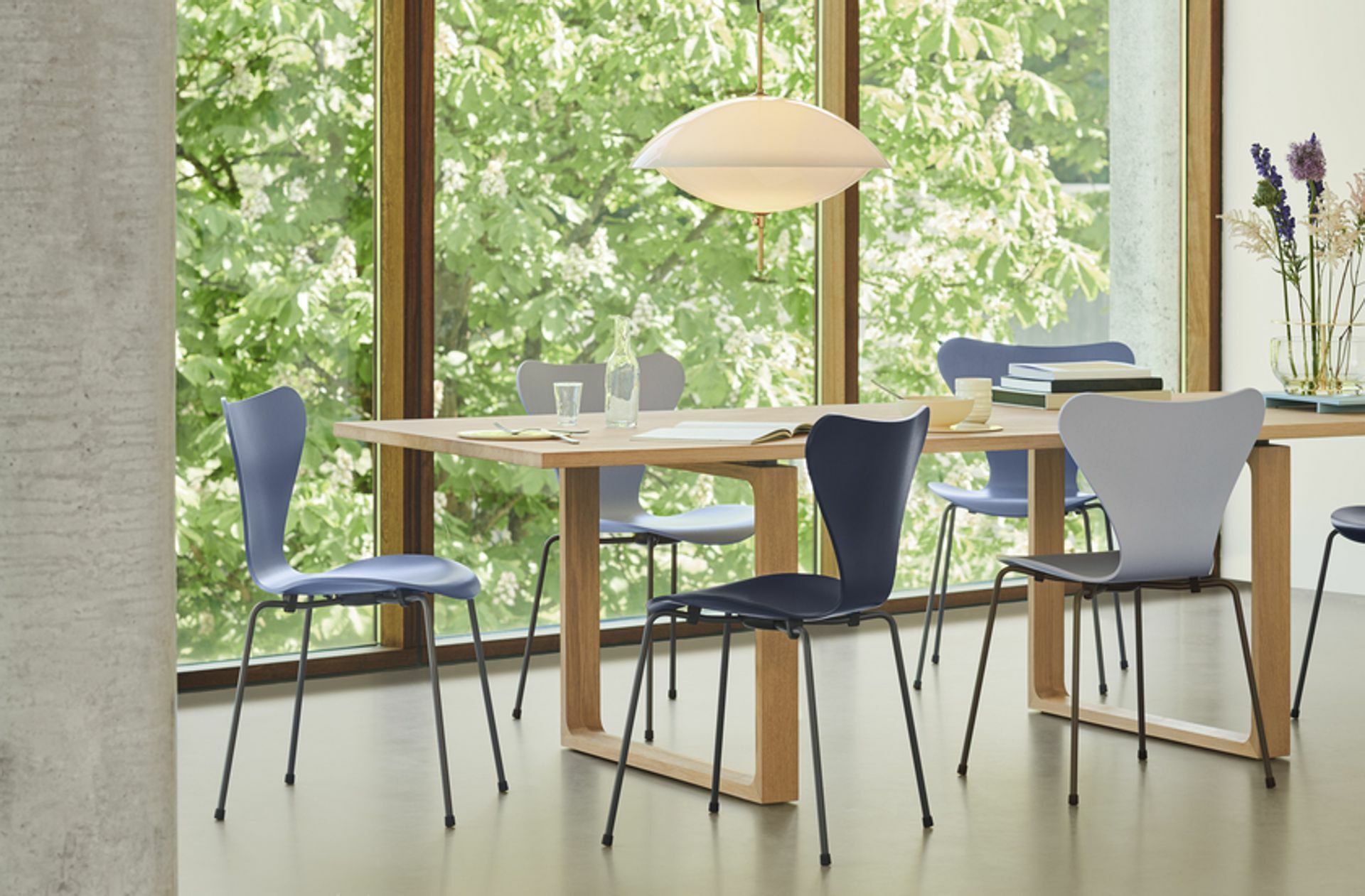 Hier ein Bild mit einem Tisch von Cecilie Hansen, dazu „Serie 7“-Stühle und die „Clam“-Leuchte.