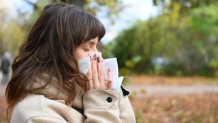 Wer niesen muss, sollte sich von anderen Personen abwenden und ein Taschentuch oder die Armbeuge vor Mund und Nase halten (Symbolbild).
