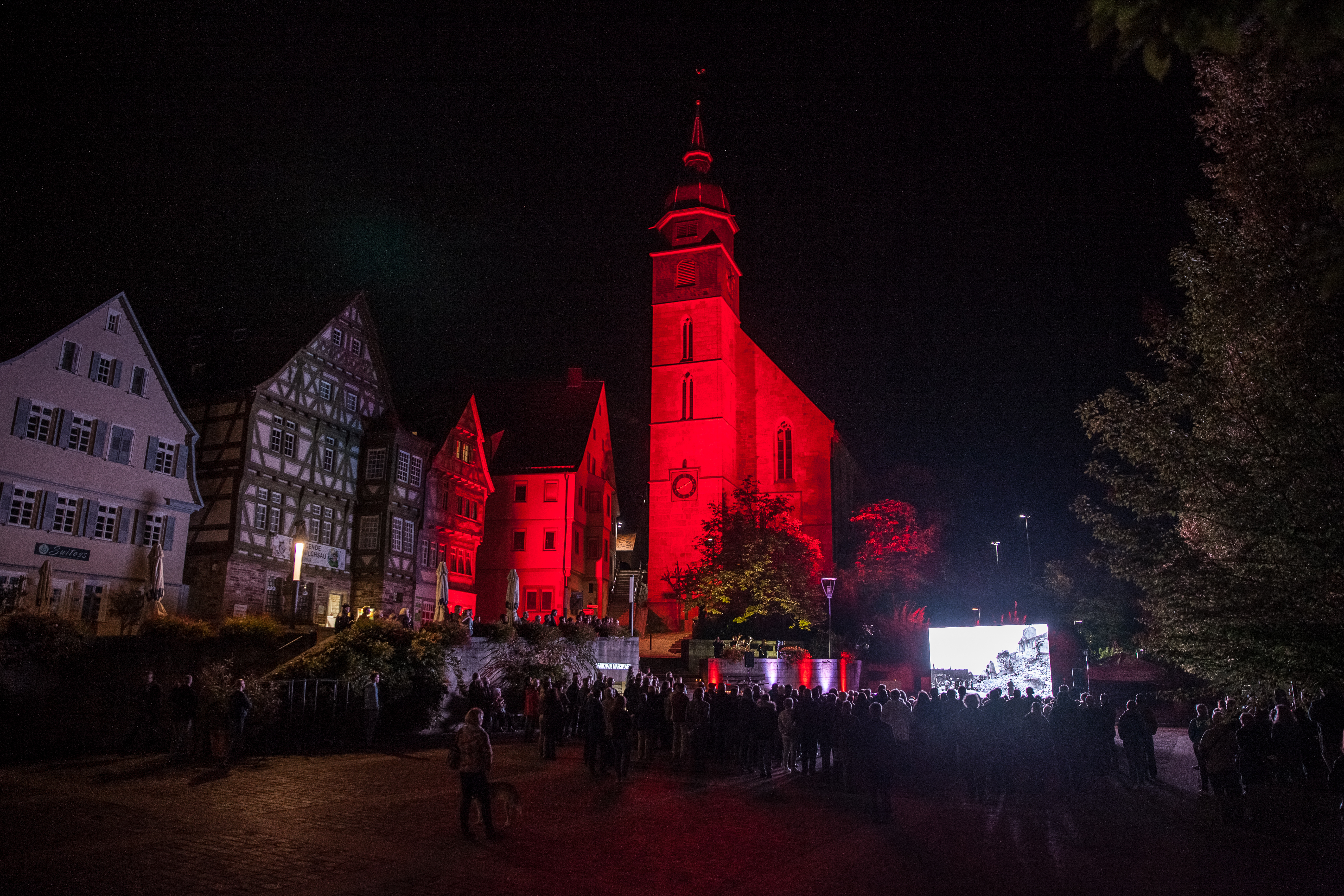 Während der Gedenkveranstaltung auf dem Marktplatz war die Böblinger Stadtkirche in rotes Licht getaucht.	Bild: fotoknobi