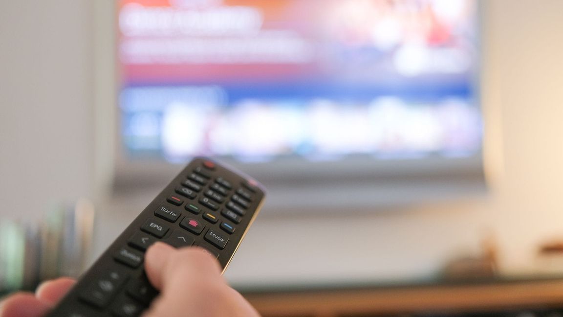 Eine Hand bedient eine Fernbedienung für ein TV-Gerät.