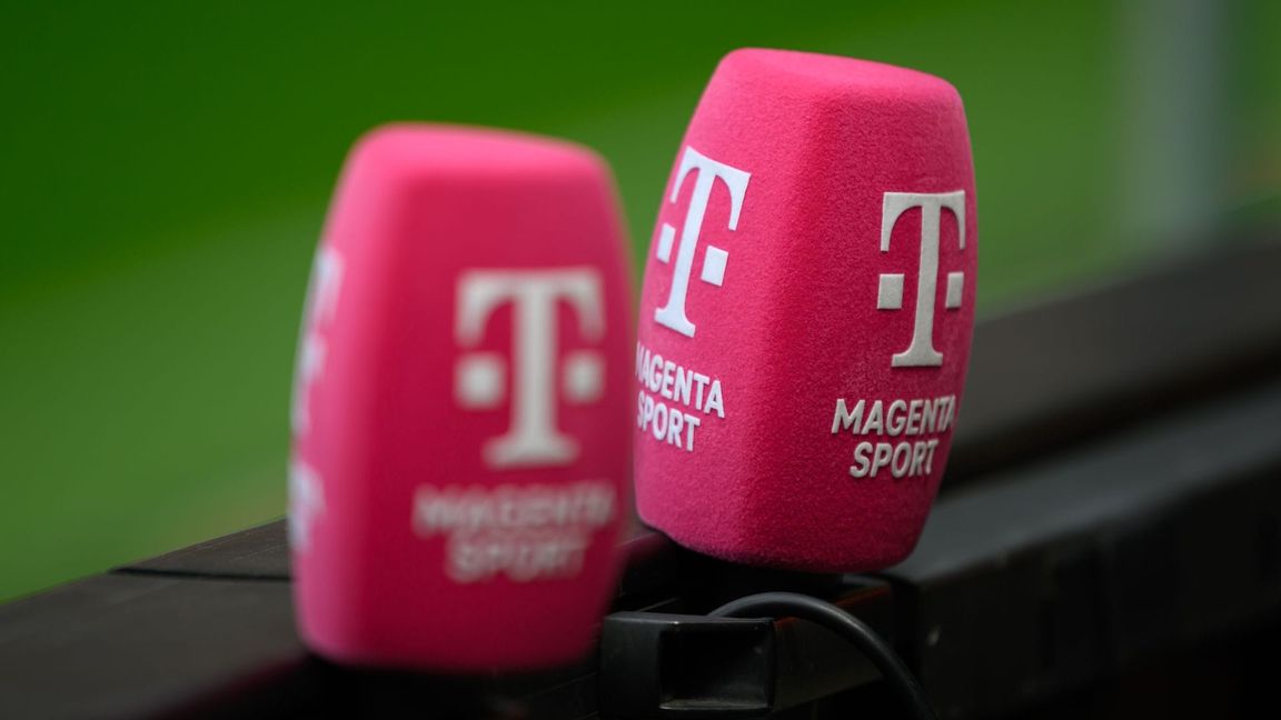Zwei Mikrofone von Magenta Sport stecken an einer Bande bei einem Fußballplatz.
