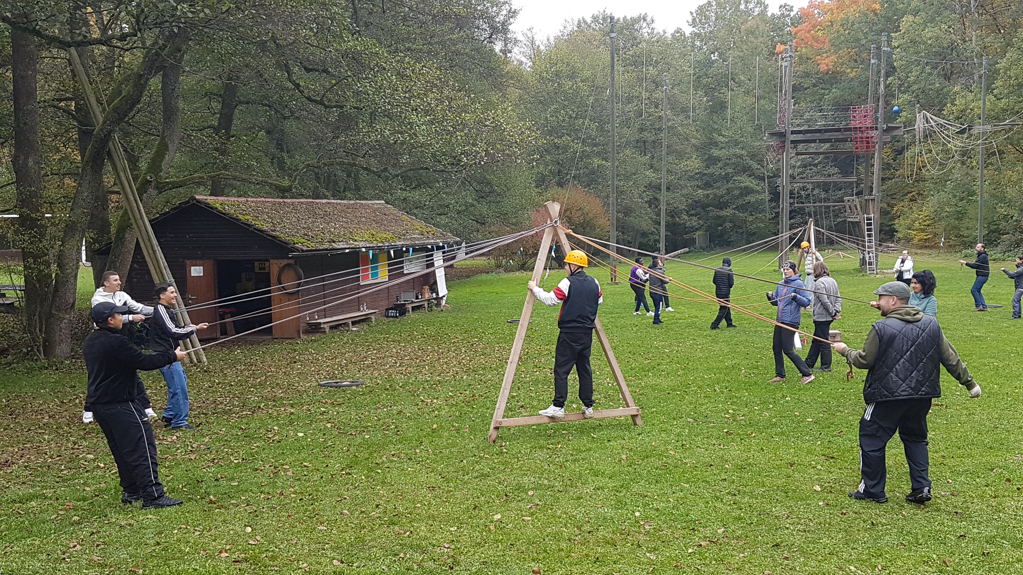 Die Schüler müssen durch gemeinsames Balancieren einen Schüler in einem Holzaufbau „Das laufende A“ vorwärtsschaukeln.     Bild: z