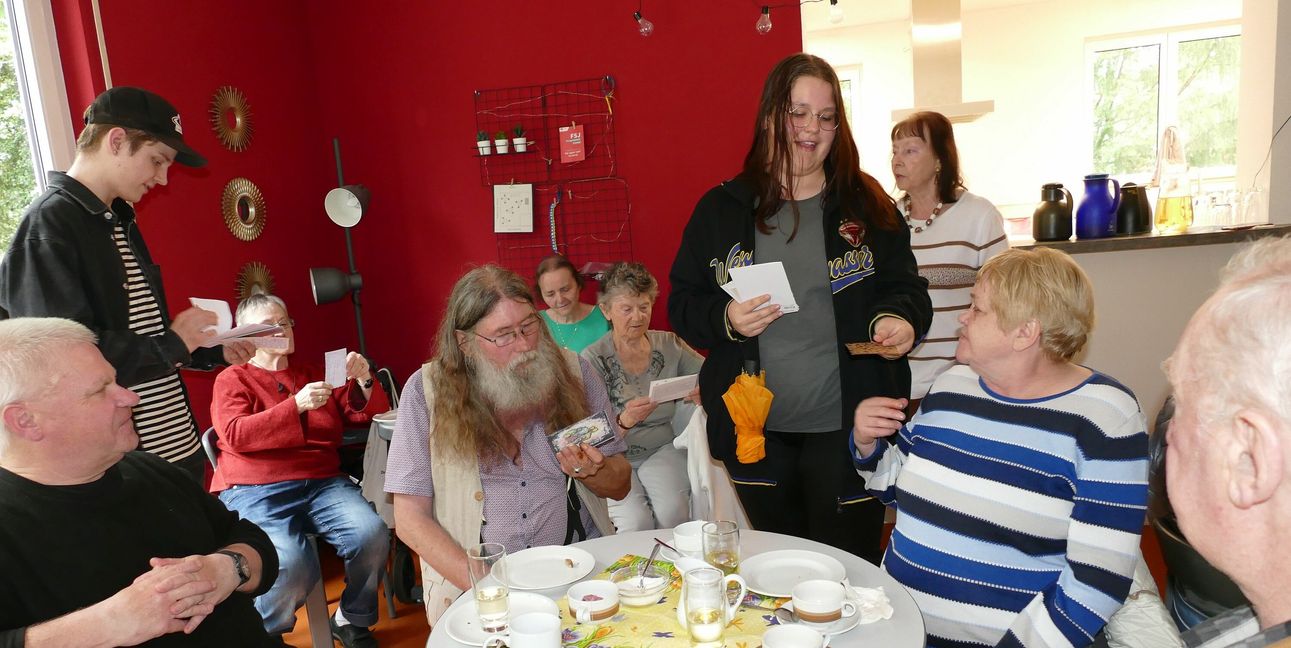 Mia Knöfel und Jaran Jaskolka verteilen Briefe unter den Gästen des Cafés Volle Kanne. Rechts hinten schaut Leiterin Anne Graf zu.
