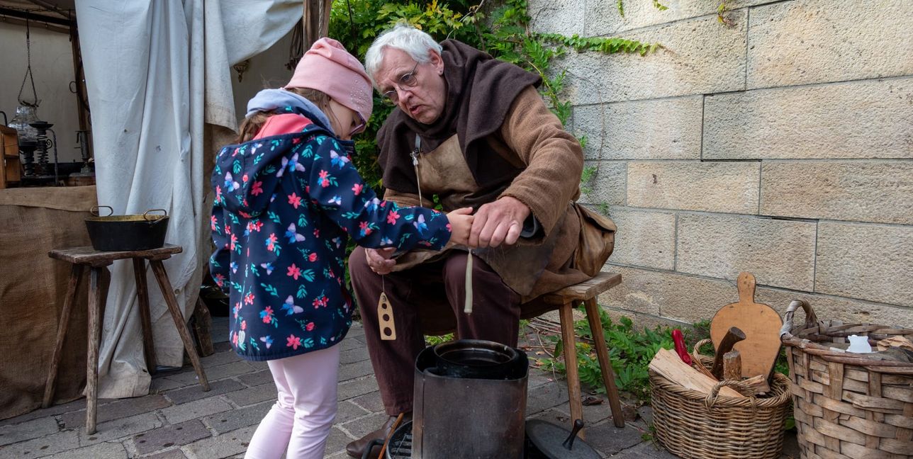 Lichtermacher Ralf Doms zeigt Cosima Kirsch, wie man früher Kerzen hergestellt hat.
