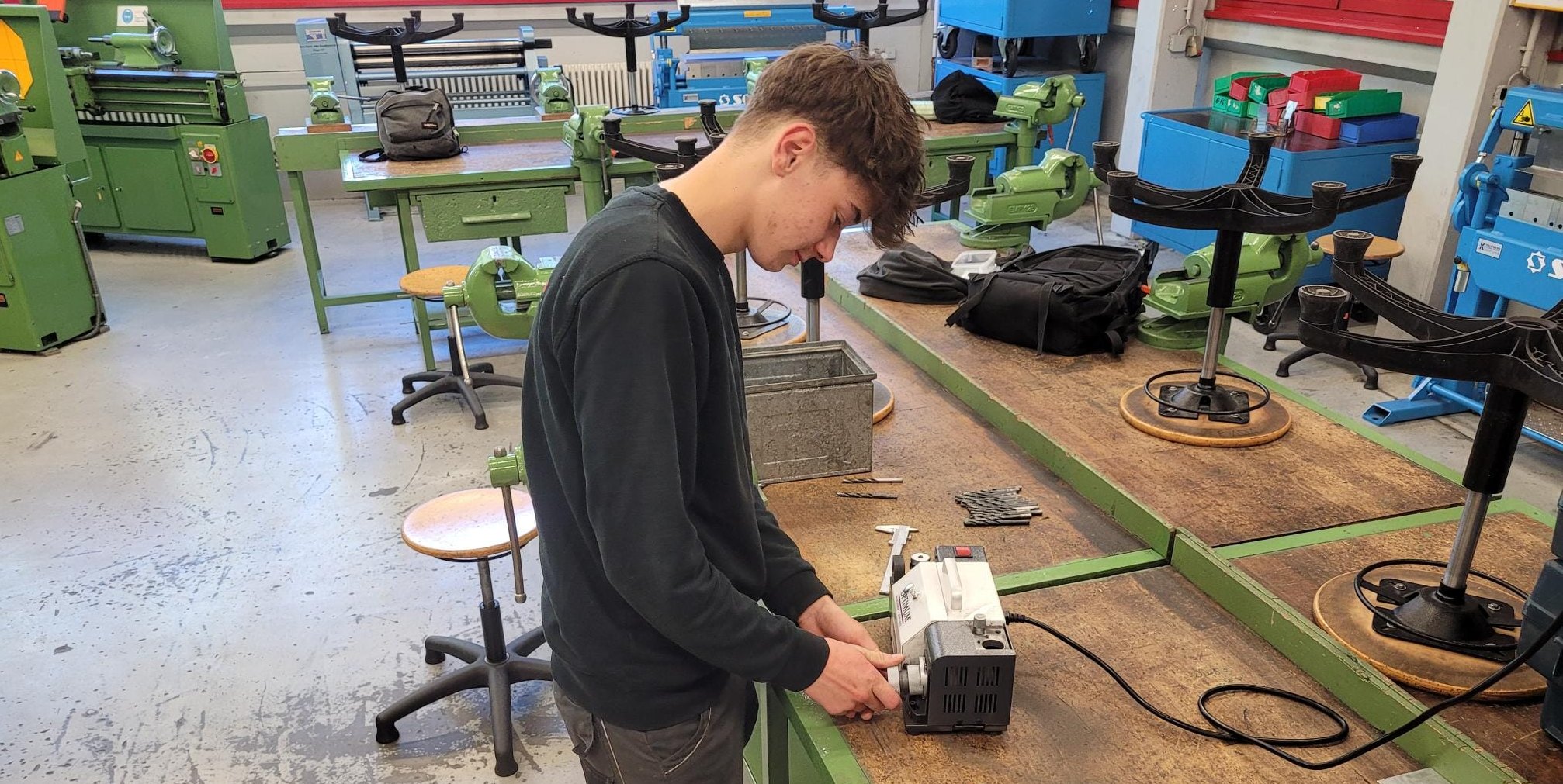 Ein Schüler schleift verbrauchte Spiralbohrer mit der neuen Bohrerschleifmaschine.
