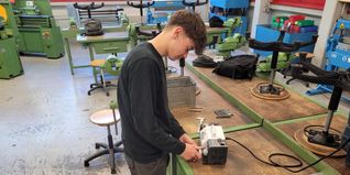 Ein Schüler schleift verbrauchte Spiralbohrer mit der neuen Bohrerschleifmaschine.