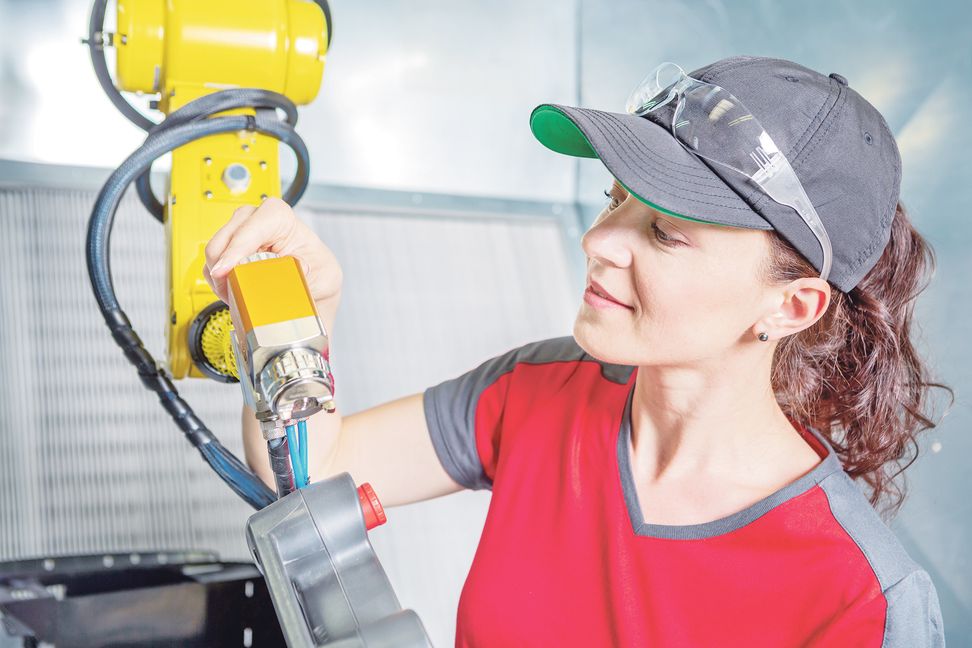 A young female technician while machine constructing in a manufacturing plant