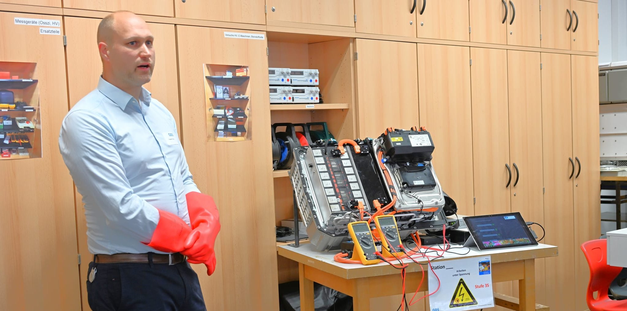 Frederik Frye vor seinem Einsatz an der Batterie eines Autos, an der er auf der Suche nach einem Defekt die Spannung innerhalb der einzelnen Zellen misst. Bild: Reichert