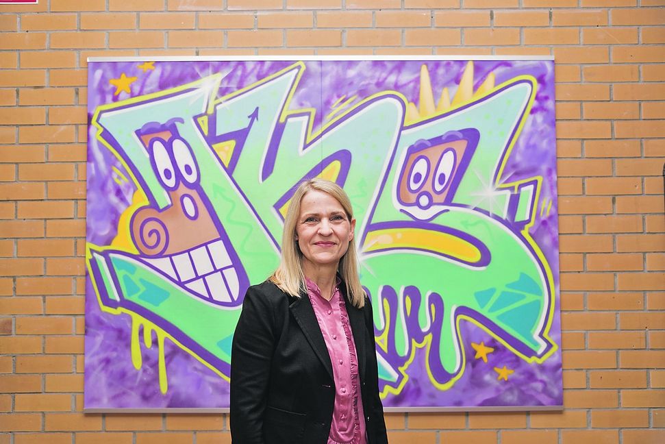 Jasmin Kellermann vor dem neuen Logo der Justinus-Kerner-Grundschule. Es wurde auf ihre Initiative und mit Unterstützung des Elternbeirats gestaltet. Bild: Nüßle