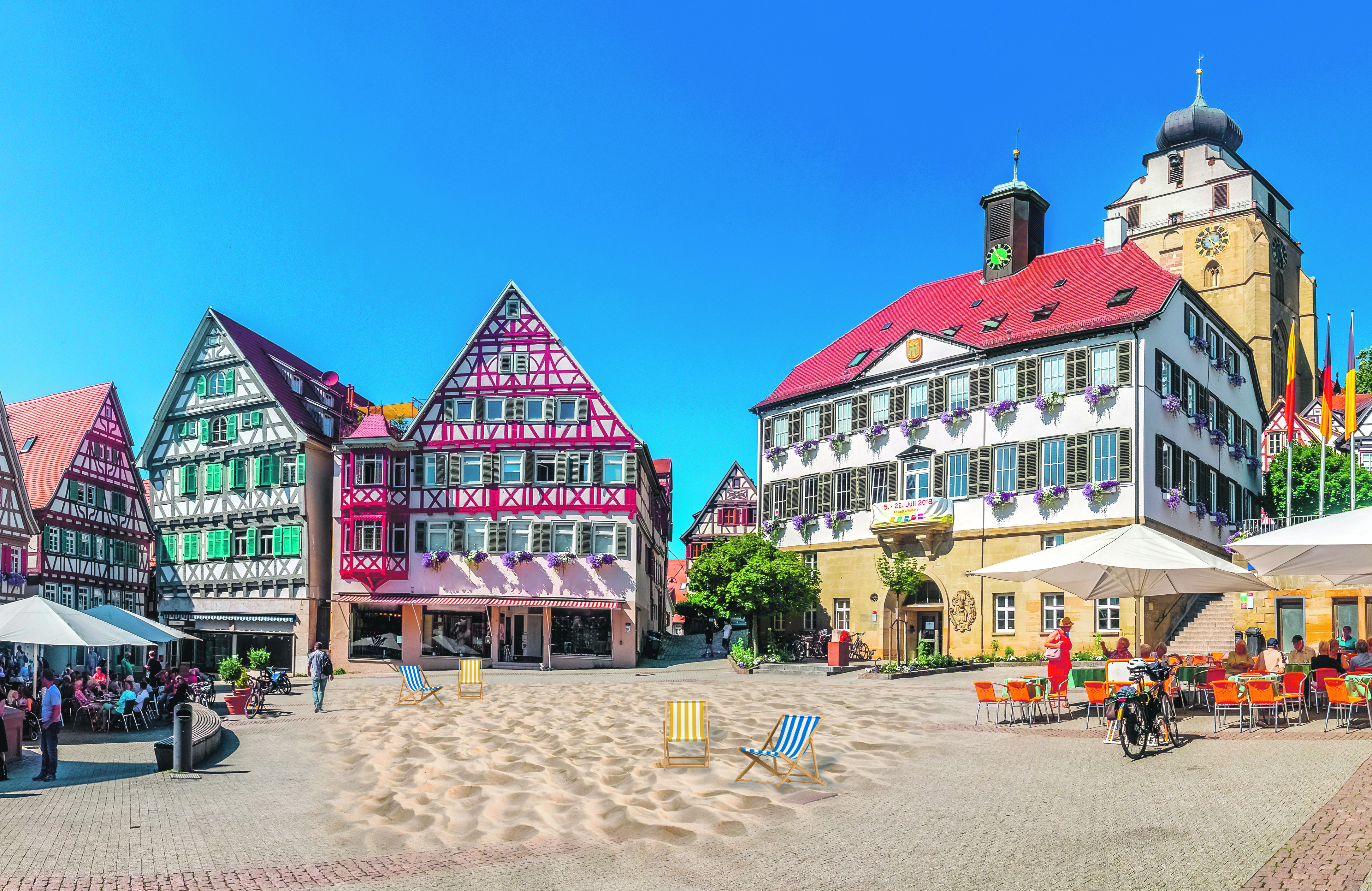 Sommer, Sand und mehr: Auf dem Herrenberger Marktplatz soll zur Haupturlaubszeit ein künstlicher Strand aufgeschüttet und „bespielt“ werden.    Montage: Sina Ettmer – stock.adobe.com/gb