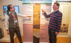 Christoph Lehnert (links) und Heinz Lüdemann vor der stratigraphischen Säule: Diese veranschaulicht die verschiedenen Bodenschichten, die sich im Lauf der Zeit übereinander abgelagert haben.