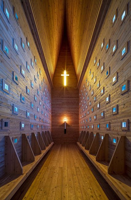 Licht fällt durch 172 quadratische, blau verglaste Öffnungen nach innen. Ein goldgelbes Kreuz durchdringt die nach Westen ausgerichtete Giebelwand der Kapelle bei Oberthürheim.
 Foto: Eckhart Matthäus © Siegf..