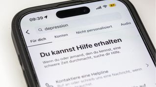 Auf einem Smartphone ist eine Suchansicht innerhalb einer Social-Media-App zu sehen, die bei dem Begriff „Depression“ Hinweise auf Hilfsangebote und Unterstützung einblendet. Plattformen wie Instagram zeigen bei sensiblen Suchbegriffen zunehmend Sicherheitshinweise und Verlinkungen zu professionellen Beratungsstellen. Sie reagieren damit auf die wachsende Rolle sozialer Medien bei der Informationssuche zu psychischen Belastungen.