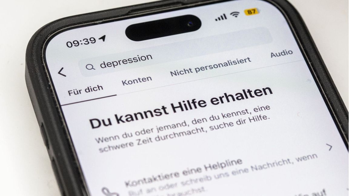 Auf einem Smartphone ist eine Suchansicht innerhalb einer Social-Media-App zu sehen, die bei dem Begriff „Depression“ Hinweise auf Hilfsangebote und Unterstützung einblendet. Plattformen wie Instagram zeigen bei sensiblen Suchbegriffen zunehmend Sicherheitshinweise und Verlinkungen zu professionellen Beratungsstellen. Sie reagieren damit auf die wachsende Rolle sozialer Medien bei der Informationssuche zu psychischen Belastungen.