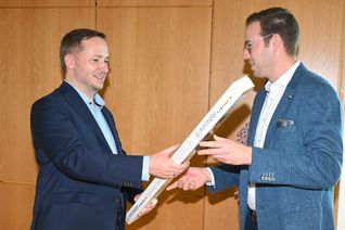 Bürgermeister Florian Glock (links) nimmt am Wahlabend die Glückwünsche seines Stellvertreters Jonas Winter und einen Meter „Nervennahrung“ (Schokolade) entgegen.