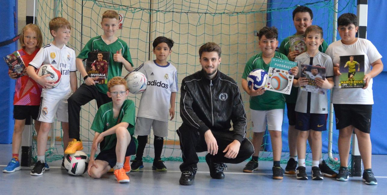 VfB-Nachwuchsstar Eliot Bujupi und die Schüler der Sindelfinger Martinsschule spielen beim Projekt „kicken & lesen“ eine Art literarischen Doppelpass.