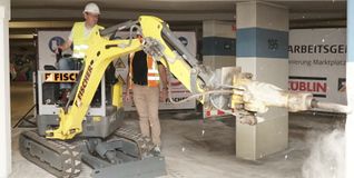 Manchmal muss man nicht nur dicke Löcher bohren: Oberbürgermeister Dr. Bernd Vöhringer bohrt sich mit dem Minibagger in eine Säule der Marktplatz-Tiegarage. Bild: Heiden