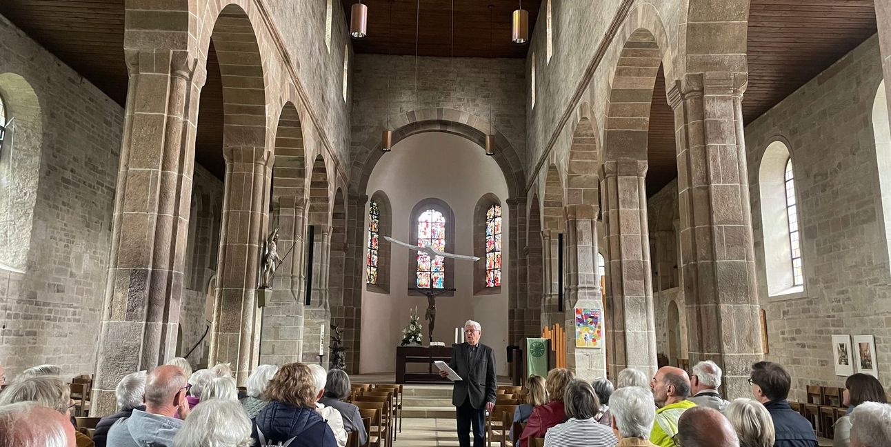 Immanuel Rühle, bei seiner ersten Führung nach sieben Jahren in der Martinskirche Sindelfingen. Der Chef des Stiftungsbeirats stellt die Themen für das Stifterfest vor, nämlich die Taube-Skulptur von Frank Teufel über ihm und die Bleiglasfenster von Walter Kohler in der Mittelapsis der Kirche.