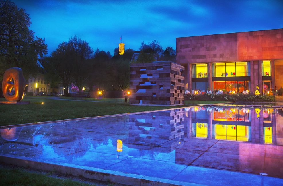 Bielefeld bei Nacht: Die Kunsthalle mit dem Skulpturenpark sowie  dem beleuchteten Turm der Sparrenburg im Zentrum der 340 000-Einwohner-Stadt in Ostwestfalen.