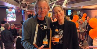 Zwei gut gelaunte Braumanufaktur-Geschäftsführer. Werner Dinkelaker präsentiert in der Holzkiste die Originalflasche, die bis zum Kinoumbau im August 2016 in alten Gemäuern steckte. Tina Gatty prostet mit einem frischen Jäger Spezial zu.