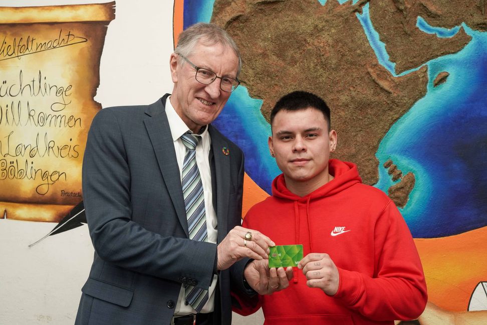 Landrat Roland Bernhard überreicht die erste Bezahlkarte an Johan Sebastian Prada Herrera.