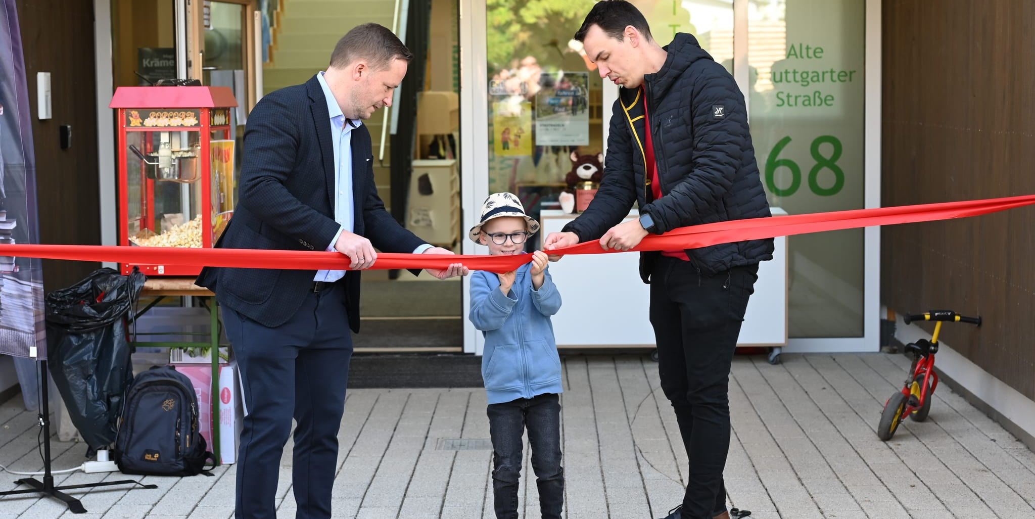 Assistiert von Bürgermeister Florian Glock (links) und Kindergartenleiter Michael Schultz durchschneidet der sechsjährige Paul bei der Einweihung das Band und macht so den Weg frei in den Kindergarten Gollenberg. Der Junge war vor drei Jahren das erste Kind, das für diesen Kindergarten angemeldet wurde.       Bild: Reichert