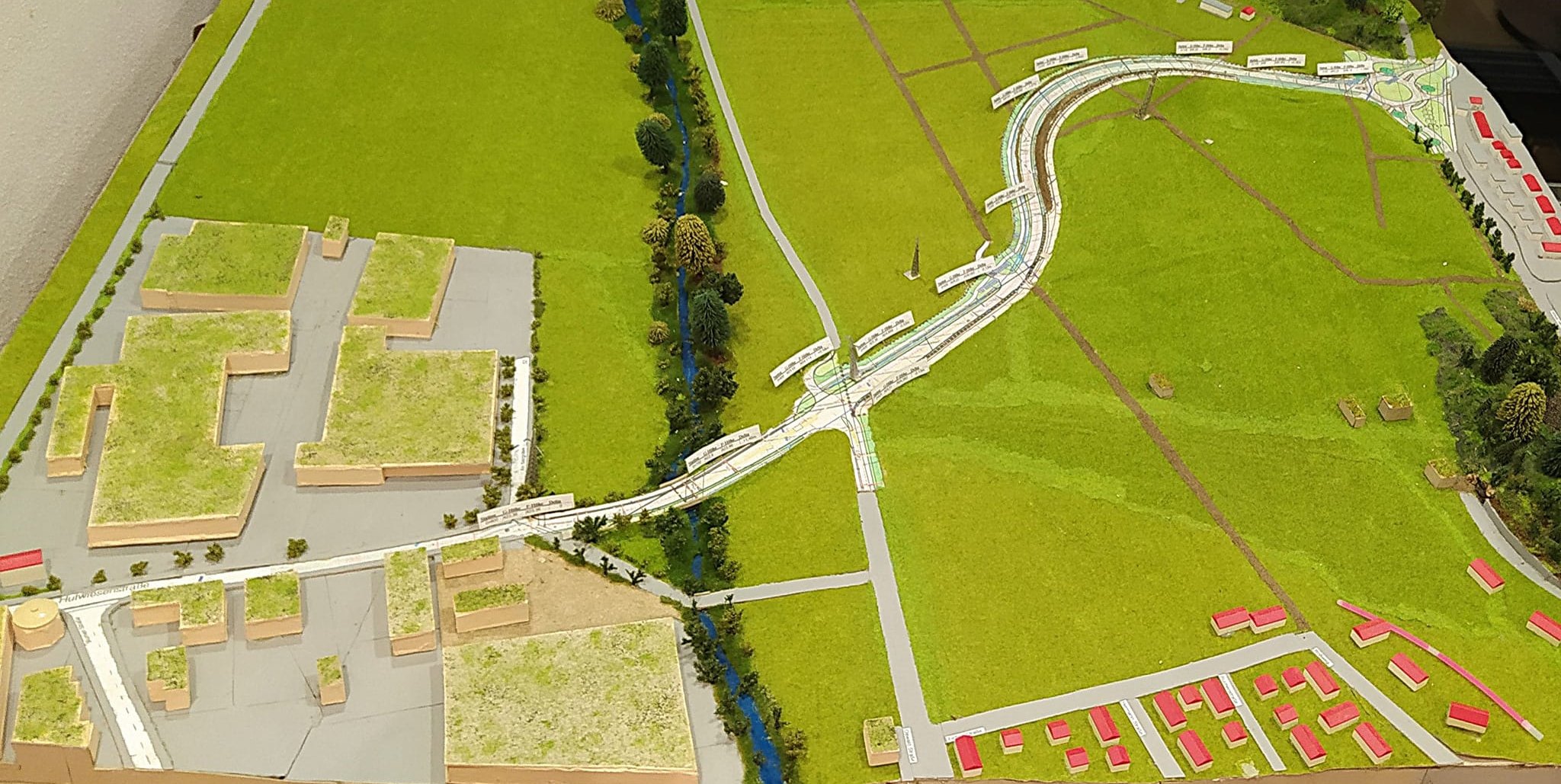 Die Osttangente (hier im Modell) führt von der Alten Stuttgarter Straße im Bogen um den Gollenberg herum hinab ins Hölzertal, überquert dort den Planbach und schließt im Gewerbegebiet Ost über die heutige Hutwiesenstraße an die Neue Stuttgarter Straße (Hölzertalstraße) an.
