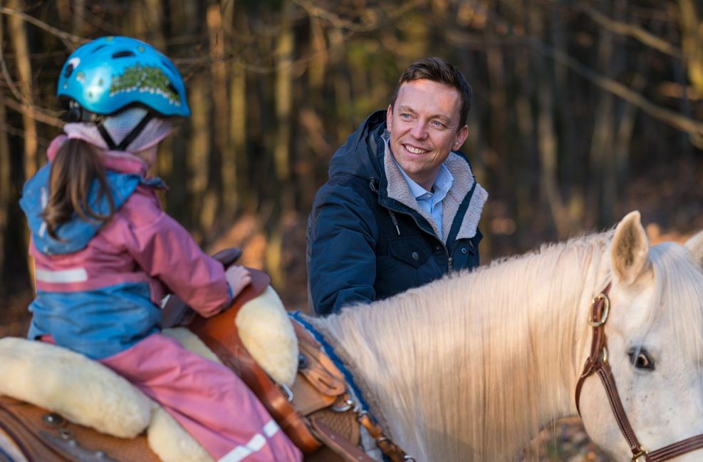 Der saarländische Ministerpräsident Tobias Hans CDU) führt ein Pferd, auf dem eine seiner Töchter sitzt.