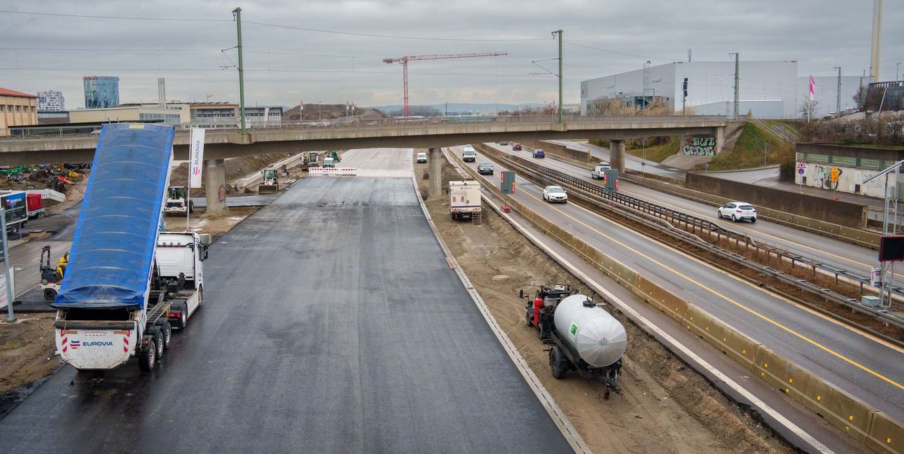 Der gesamte Autobahnverkehr wird auf die im Bild linke Seite verlegt. Pro Fahrtrichtung stehen dann zwei Spuren zur Verfügung. Die Betonfahrbahn (die helle Fahrbahn hinten im Bild) erstreckt sich von der Brumme-Allee bis zur Bahnbrücke. Die provisorische Asphaltfahrbahn (die dunkle Fahrbahn vorne im Bild) schließt daran an und führt den Verkehr bis kurz vor das westliche Tunnel-Portal.